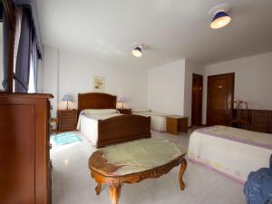 a bedroom with two beds and a coffee table at Hotel Restaurante Xaneiro in Melide