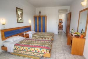 um quarto de hotel com duas camas e uma secretária em Kassandra Hotel em Ialyssos