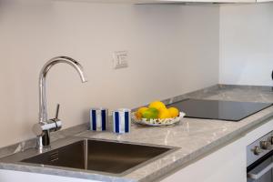 a kitchen counter with a sink and a bowl of fruit at Castalia Apartments & Rooms Duomo Taormina in Taormina