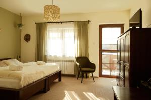a bedroom with a bed and a chair and a window at Karczma Karnasów in Cisna