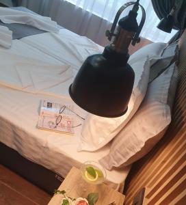 a black lamp on a bed with a drink and a table at Kamelia guest rooms in Kazanlŭk