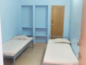 two beds in a room with blue walls and a door at Zama Lodge in Chennai