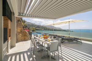 a patio with a table and chairs and a view of the ocean at Villa Grandview by Villa Plus in Funchal