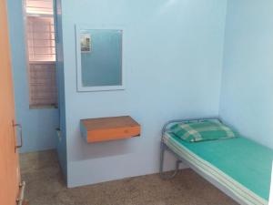 a small room with a small bed and a mirror at Zama Lodge in Chennai