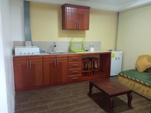 a kitchen with wooden cabinets and a sink and a couch at Hospedaje Wiruyana in Cotacachi