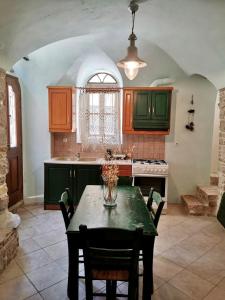 uma cozinha com armários verdes e uma mesa com cadeiras em Yi artistry 1-bedroom medieval holiday house em Kalamoti