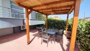 a patio with a table and chairs under a wooden pergola at Petite Sirene Studios in Paralia Katerinis