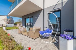 a patio with a swing and chairs on a house at Apartament Rowerowo przez Mierzeję, rowery gratis in Sztutowo