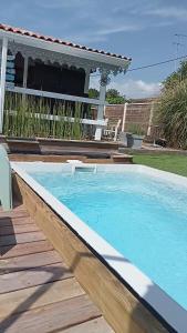 una gran piscina con terraza de madera y una casa en La cabane et sa cascade, en Lège-Cap-Ferret