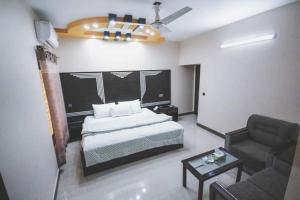 Royal Accommodation في كراتشي: غرفة نوم بسرير وكرسي وأريكة