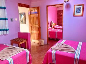 Habitación rosa con 2 camas y espejo. en Hotel Cazomalli Oaxaca, en Oaxaca City