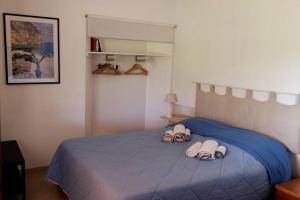 a bedroom with a blue bed with two slippers on it at Countryside villa in Sardinia in Triei
