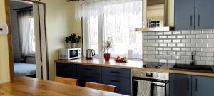 a kitchen with blue cabinets and a table with a microwave at Kärdla Vabaduse Holiday Apartment with Garden in Kärdla