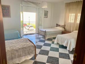 Un dormitorio con dos camas y suelo de cuadros. en Casa Nati, en Alfarnate