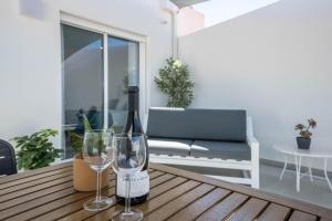 Sunset Apartment في ساغريس: زجاجة من النبيذ وكأسين على طاولة خشبية