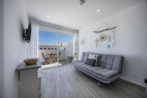 a living room with a couch and a large window at Sunset Apartment in Sagres