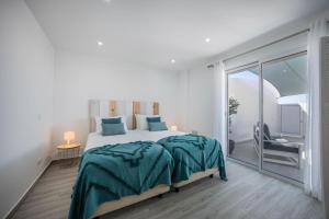 a white bedroom with a large bed and a balcony at Sunset Apartment in Sagres