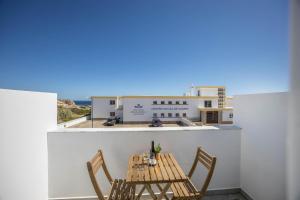 a table and chairs on a balcony with a building at Sunset Apartment in Sagres