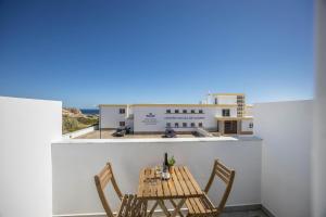 a table and chairs on a balcony with a building at Sunset Apartment in Sagres