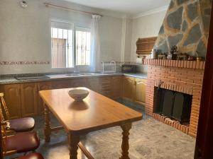 cocina con mesa de madera y chimenea en Casa Nati, en Alfarnate
