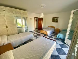 Un dormitorio con dos camas y suelo de cuadros. en Casa Nati, en Alfarnate
