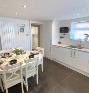 a kitchen with a table and chairs in a kitchen at Modern 4-bed Cottage Llanwrst Town Centre & Parking - Snowdonia! near Betws-y-Coed in Llanrwst