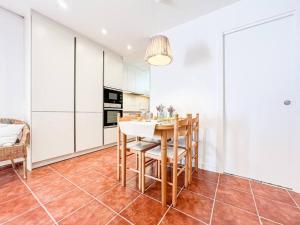 a kitchen with white cabinets and a table and chairs at Apartament 'Es Botànic' in Blanes