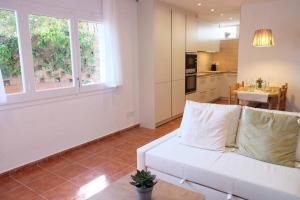 a living room with a white couch and a kitchen at Apartament 'Es Botànic' in Blanes