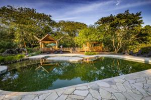 a pool in a garden with a gazebo at Banana Bamboo Ecolodge in Ubatuba