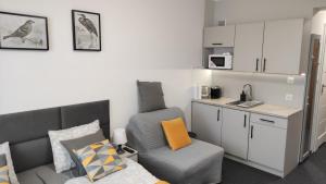 een woonkamer met een stoel en een keuken bij Apartament 301 Planeta in Mielno