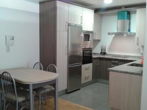 kuchnia ze stołem i lodówką ze stali nierdzewnej w obiekcie Apartamento Rural Arluzepe w mieście Echarri-Aranaz