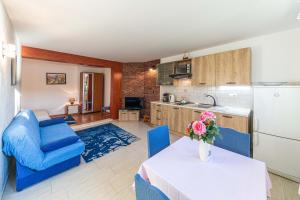 a kitchen and living room with a table and blue chairs at Rajcic Apartments in Rogoznica