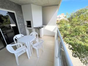 邦比尼亞斯的住宿－Refúgio da Lagoinha - Centro de Bombinhas，阳台配有白色的桌椅。