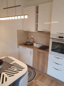 uma cozinha com armários brancos e um forno com placa de fogão em Apartman Bečići - Budva em Budva