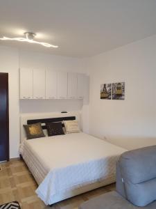 um quarto com uma cama branca e uma cadeira azul em Apartman Bečići - Budva em Budva