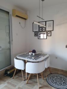uma sala de jantar com uma mesa e 2 cadeiras brancas em Apartman Bečići - Budva em Budva