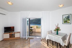 a living room with a dining room table and a television at Rajcic Apartments in Rogoznica