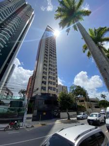 um edifício alto com o sol brilhando sobre ele em Flat a margem do açude velho em Campina Grande