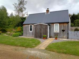 a small wooden house with a grass yard at Small cosy bothy in Dingwall