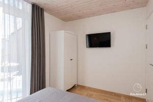 a bedroom with a bed and a tv on a wall at Čiki Puki Pajūrys in Palanga