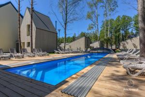 a swimming pool with lounge chairs next to a wooden deck at Čiki Puki Pajūrys in Palanga