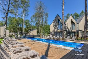 a swimming pool with lounge chairs in front of a house at Čiki Puki Pajūrys in Palanga