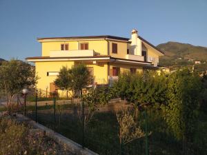 a yellow house with a fence in front of it at B&B Il Dolce Nido in Tortora