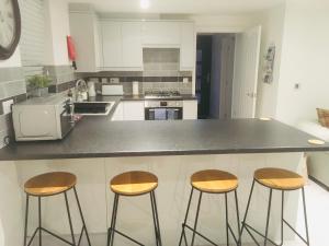 a kitchen with three bar stools and a counter at Huntingdon Apartment in Huntingdon