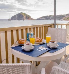 a table with a breakfast of croissants and orange juice at Hotel Regina del Mare in Ischia