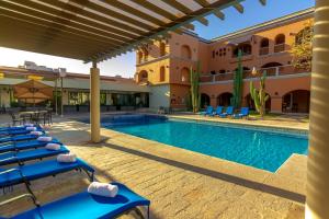 una piscina del resort con sedie a sdraio blu e un edificio di Gamma Guaymas Armida Hotel a Guaymas