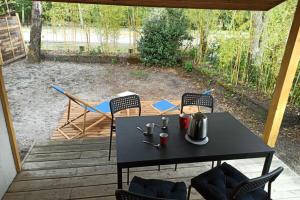 a black table and chairs on a patio at Cozy chalet des Moussaillons N99 - proche lac in Hourtin