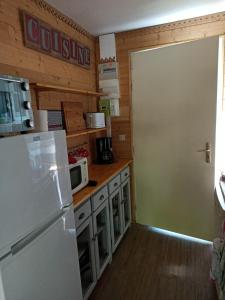 eine Küche mit einem weißen Kühlschrank und einer Mikrowelle in der Unterkunft Cozy chalet des Moussaillons N99 - proche lac in Hourtin