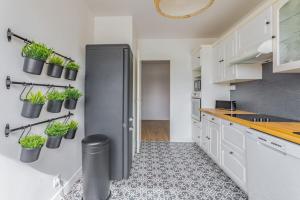 une cuisine avec réfrigérateur et plantes en pot sur le mur dans l'établissement Appart'Hôtel Luminous Vue Seine- Paris 15min, à Juvisy-sur-Orge