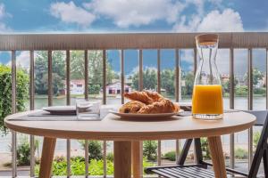 a table with a plate of food and a glass of orange juice at Appart'Hôtel Luminous Vue Seine- Paris 15min in Juvisy-sur-Orge